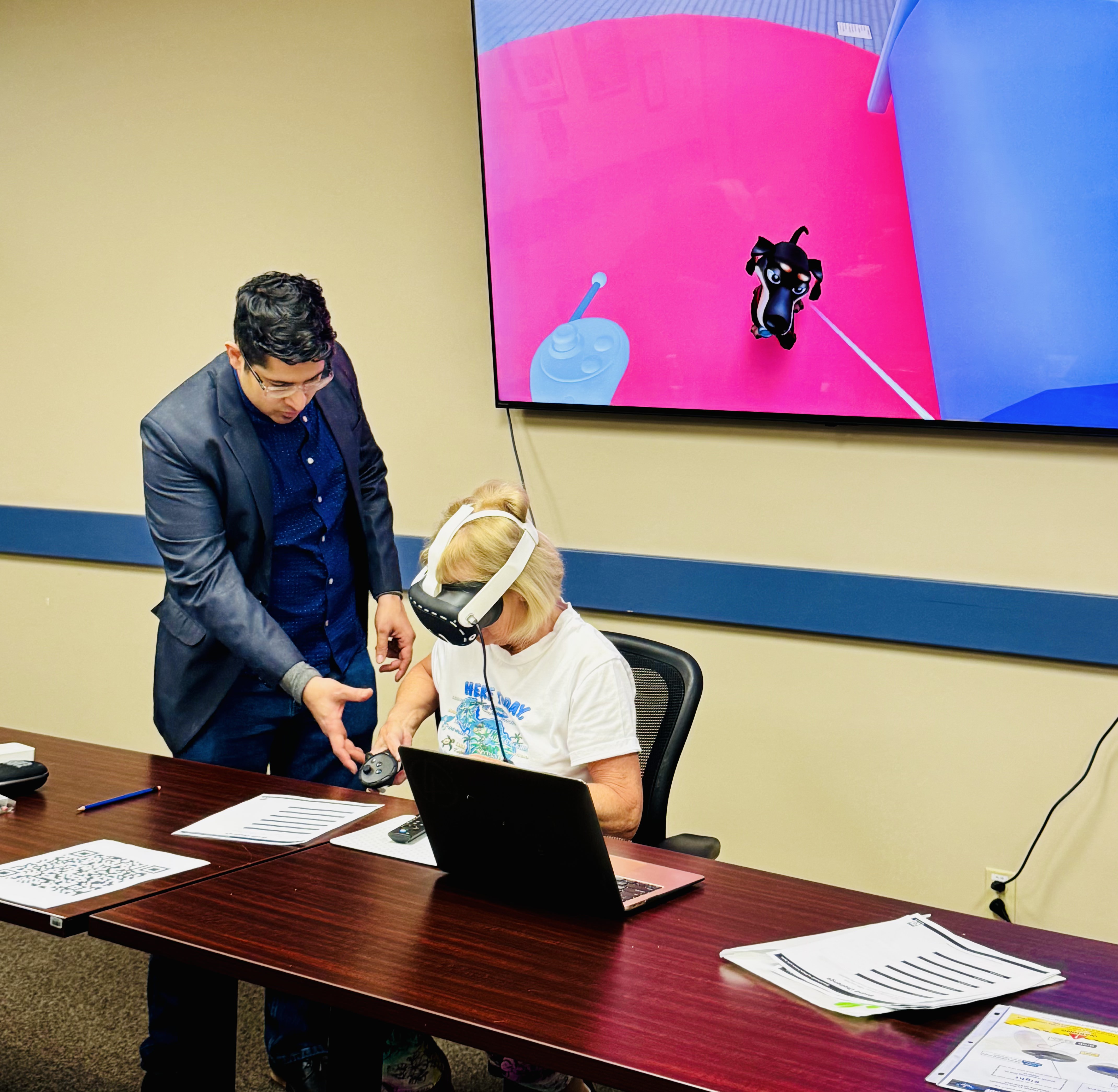 Simple French with Hems facilitator guiding a Immersive Mind & Memory Program (IMMP) activity beside a shared display